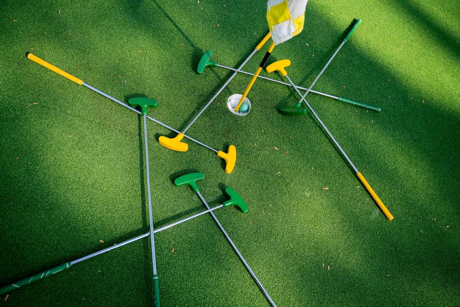 Colorful putters scattered around a hole on a putting green
