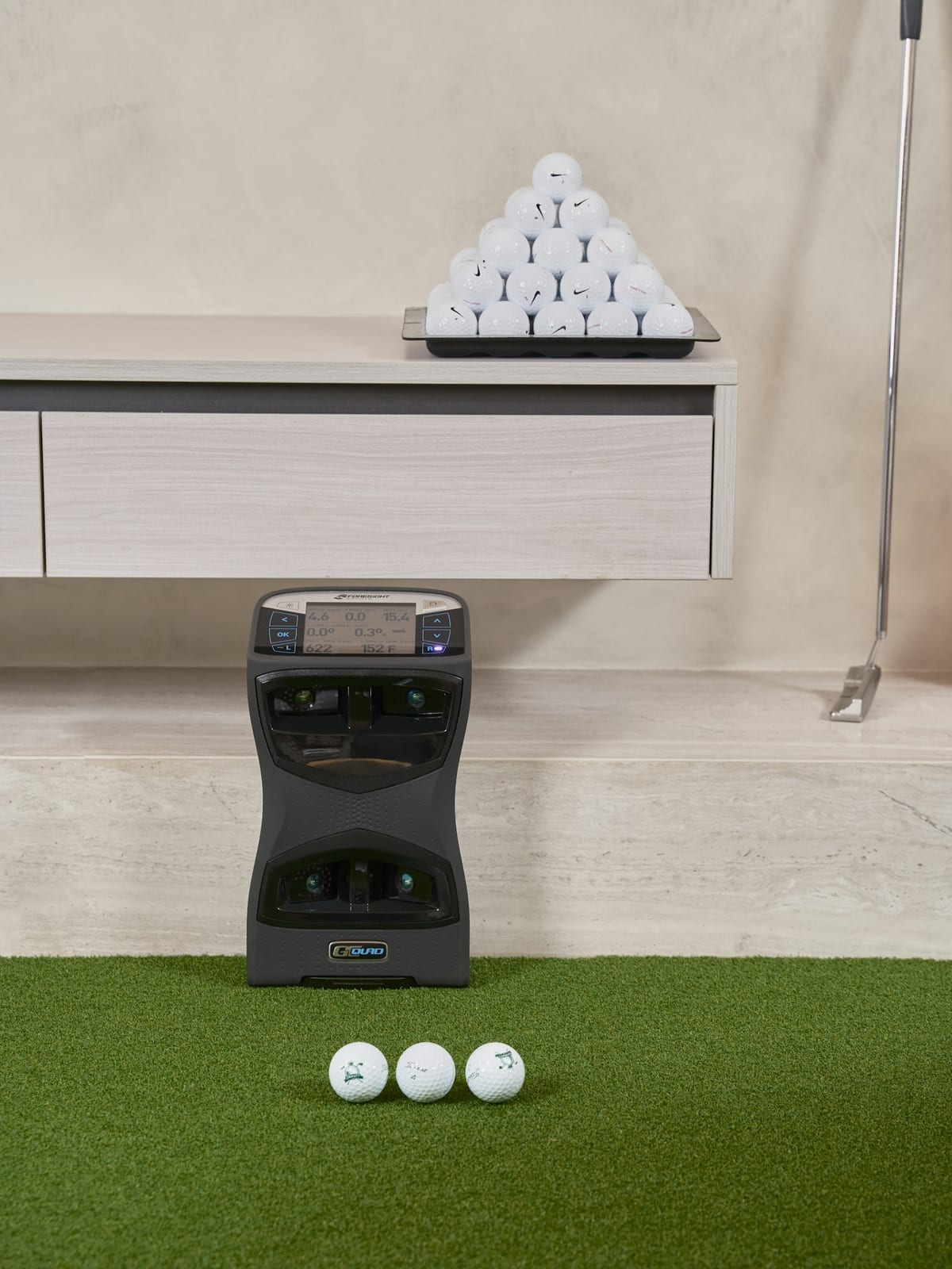 A golf impact screen stretched across the front of a simulator bay above a hitting turf