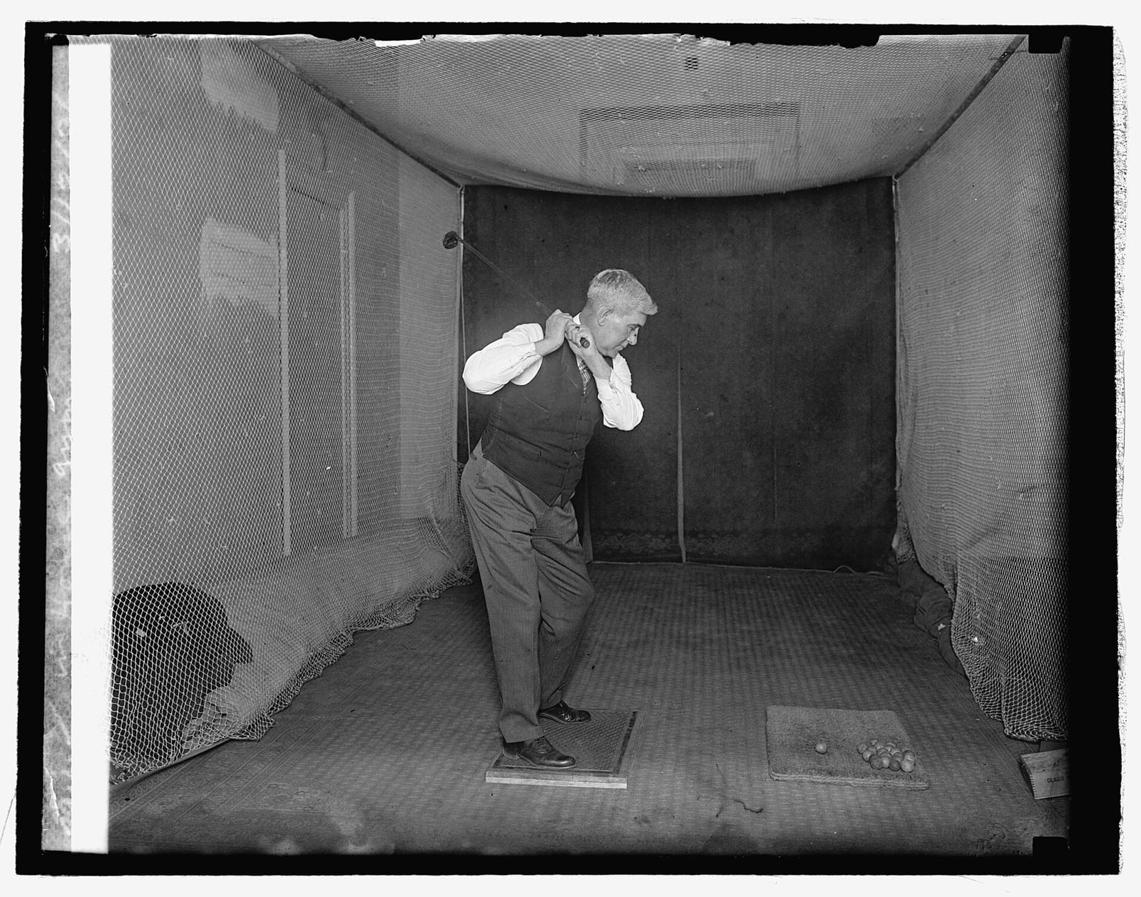 A historic black-and-white photo of a member of Congress practicing indoor golf in a House gym