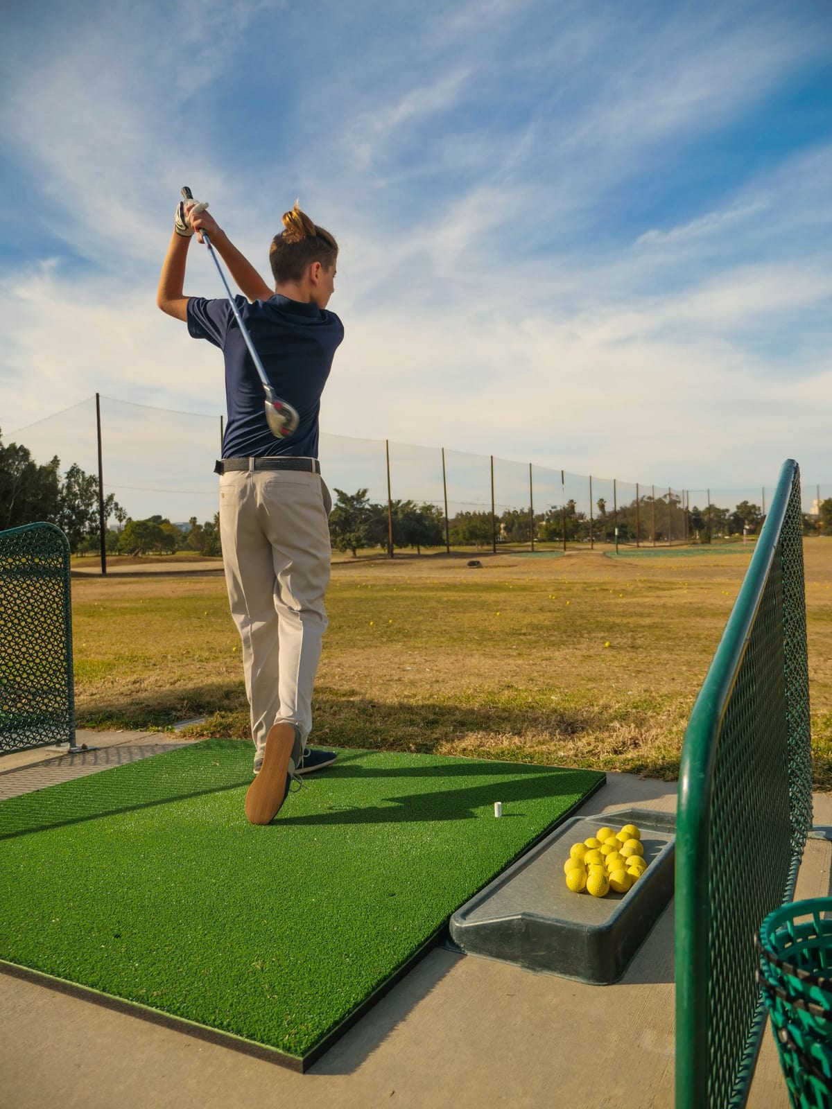 A young golfer in the finish position of a full golf swing