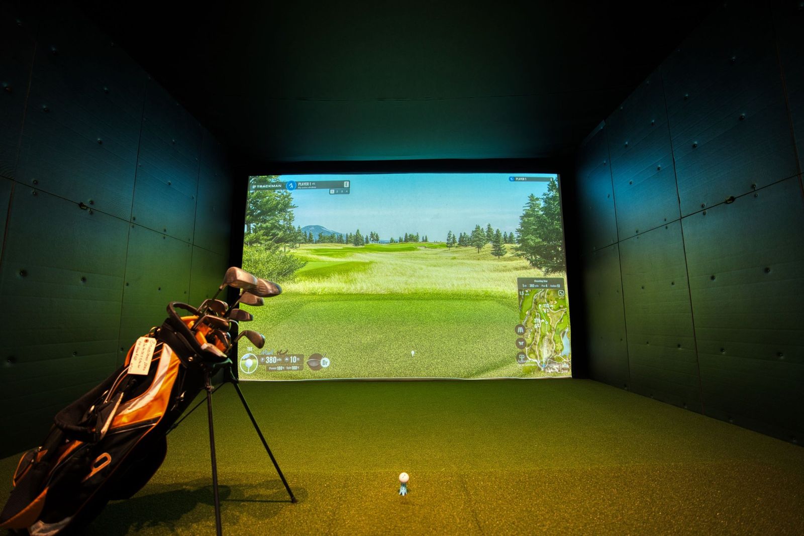 A modern indoor golf simulator room with a projector screen